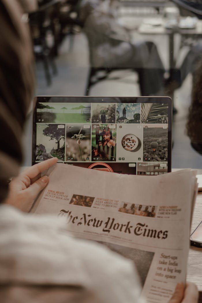 about-01 Woman reading The New York Times with a laptop displaying images in a café setting.