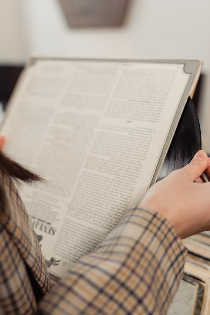gallery-4 A close-up of a person holding a vintage vinyl record in a store, evoking a classic music vibe.